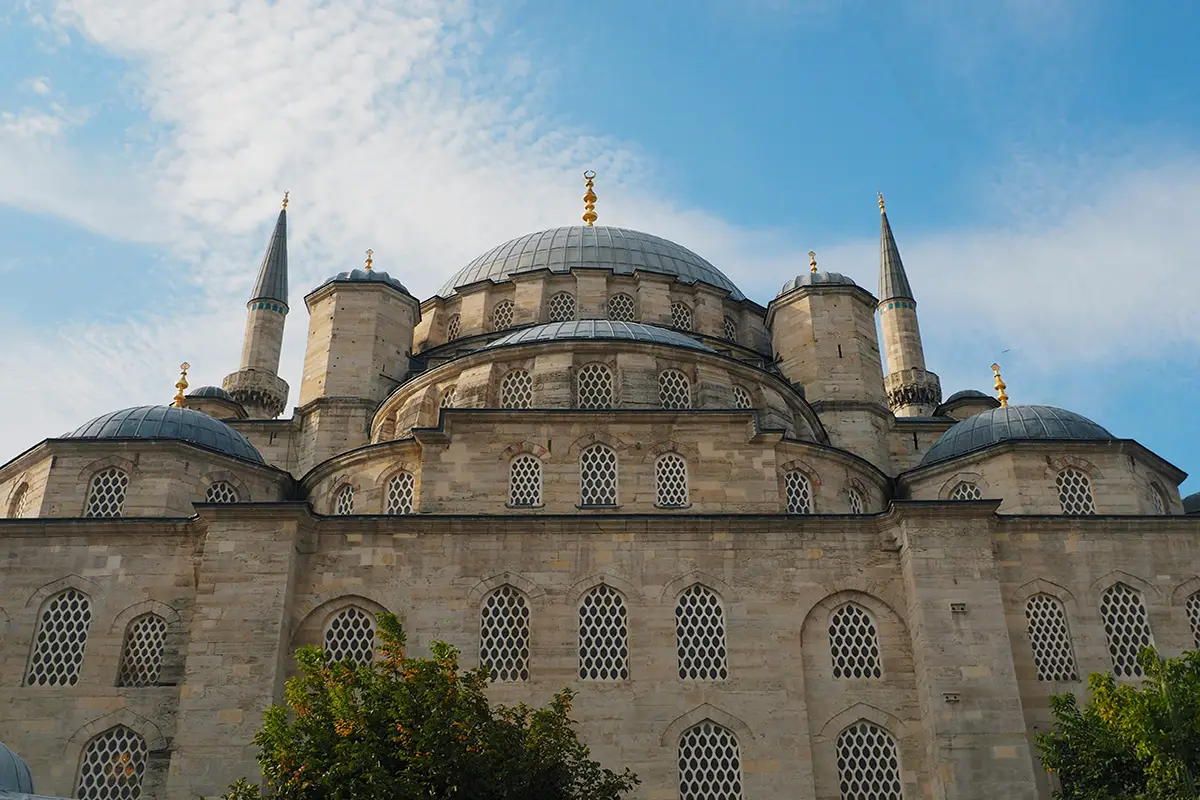 Grand stone mosque with domes and minarets.