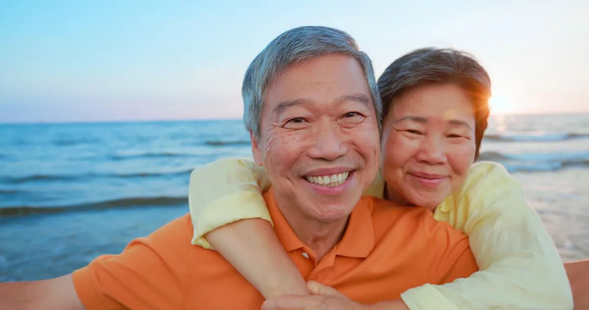 Elderly Asian couple taking a picture by the sea.